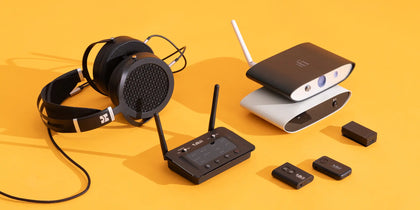 Black headphones, wireless routers, and small devices on an orange background.
