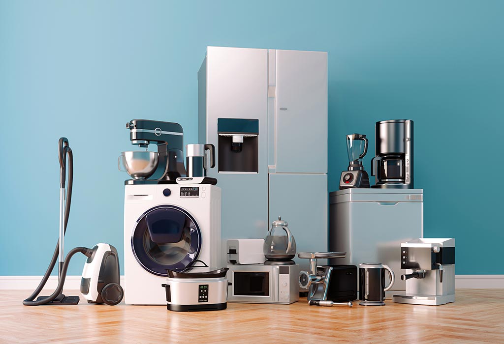 A variety of modern kitchen appliances on a wooden floor against a blue wall.