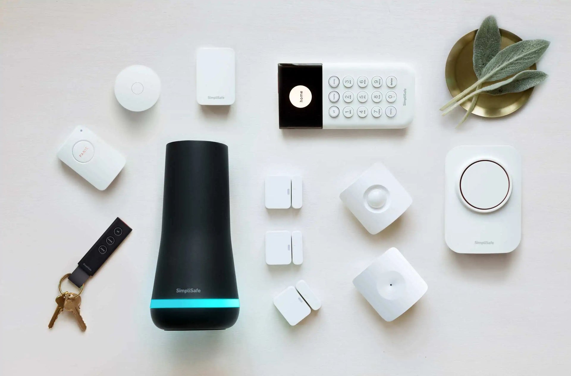 Smart home devices on a table, featuring a black speaker, white gadgets, and a gold bowl.