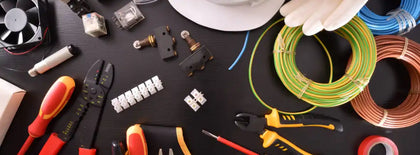 Electrical tools and supplies on a black surface, including wires, pliers, and gloves.