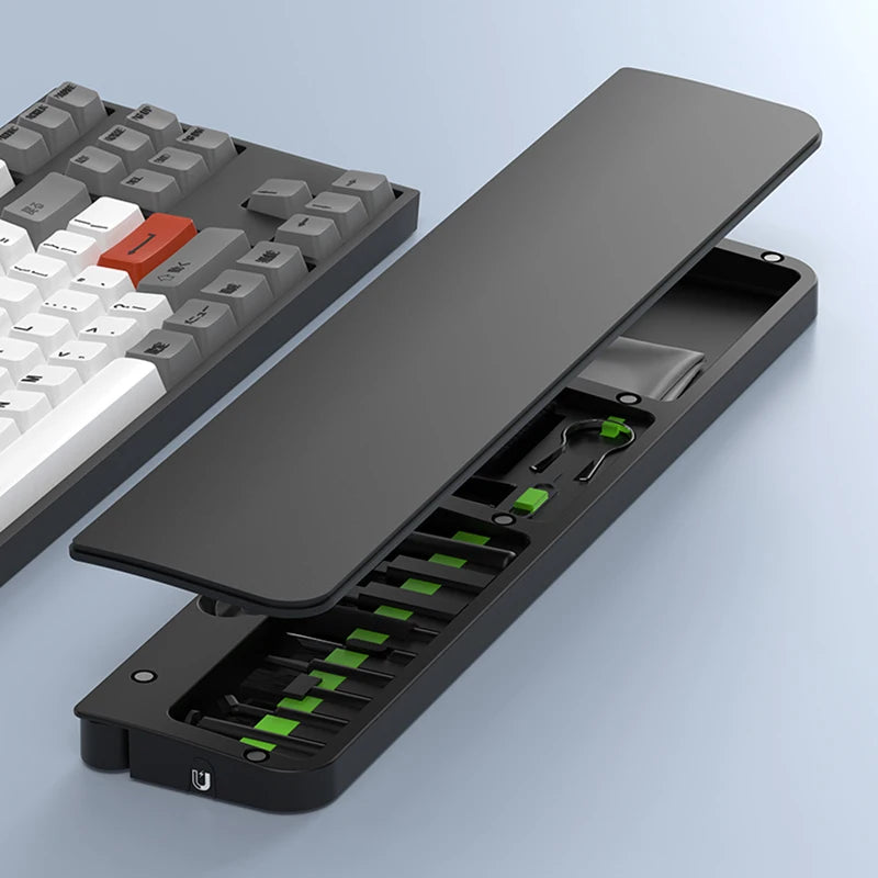 Open black case with green accents beside a gray and white keyboard on a light blue surface.