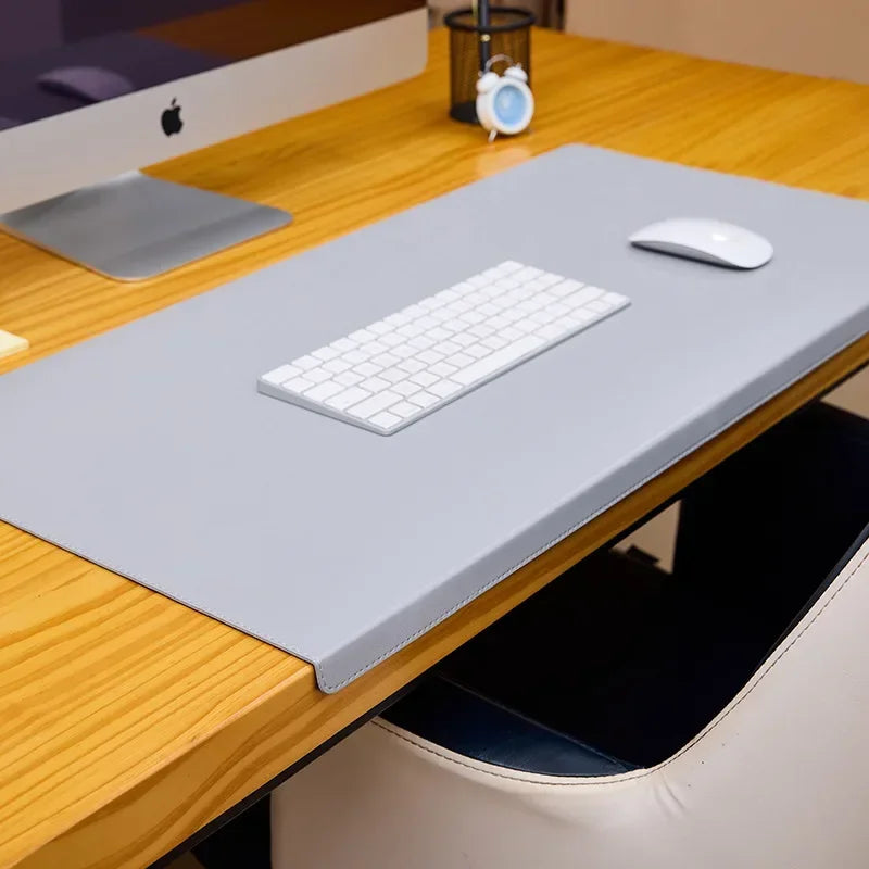 A wooden desk with a computer, gray mat, white keyboard, and mouse.
