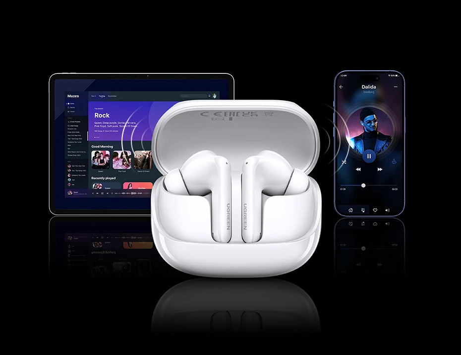 White wireless earbuds in an open case, with a tablet and smartphone in the background.
